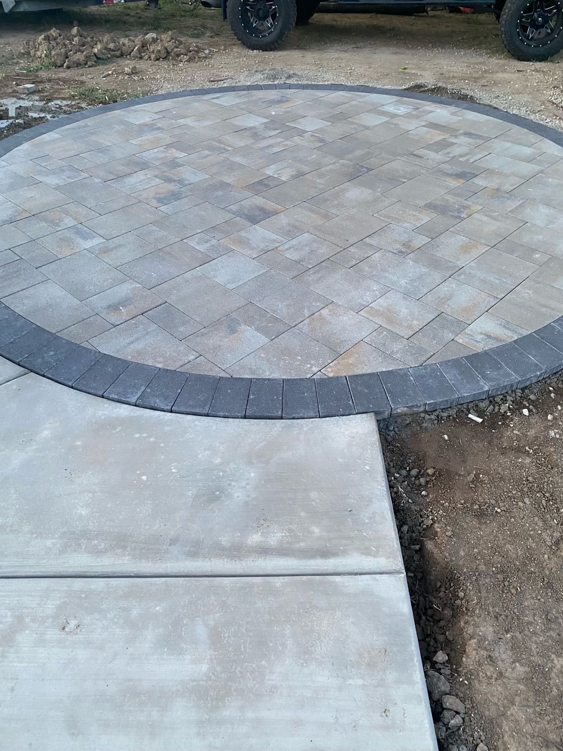 A circular brick walkway with a car parked in the background.