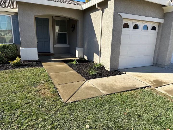 A house with a white garage door and a sidewalk in front of it.