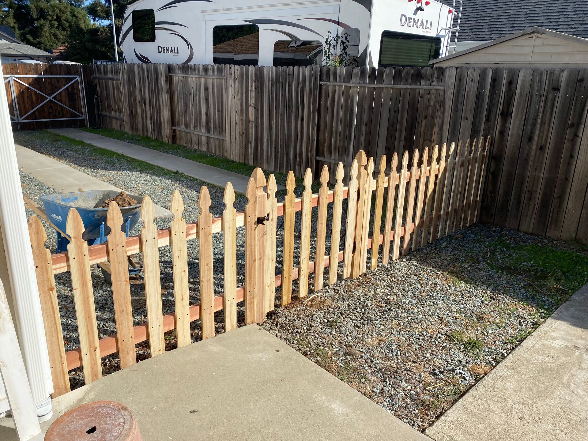 A wooden picket fence with a trailer in the background