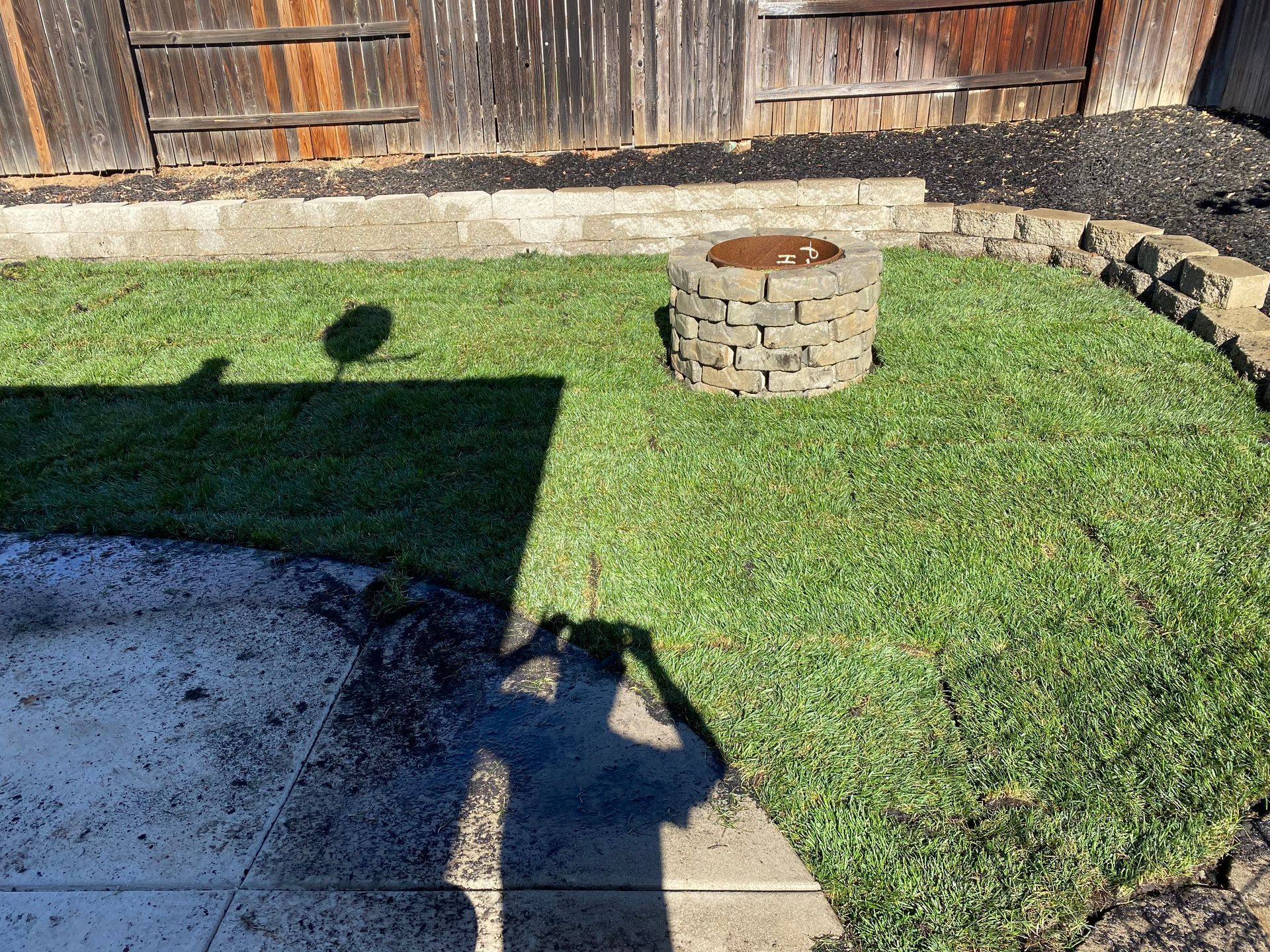 A fire pit is sitting in the middle of a lush green lawn.