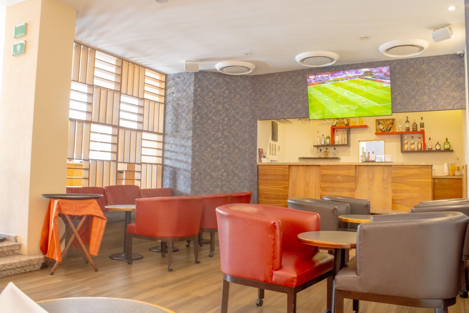 Un bar-salón con sillones rojos y grises