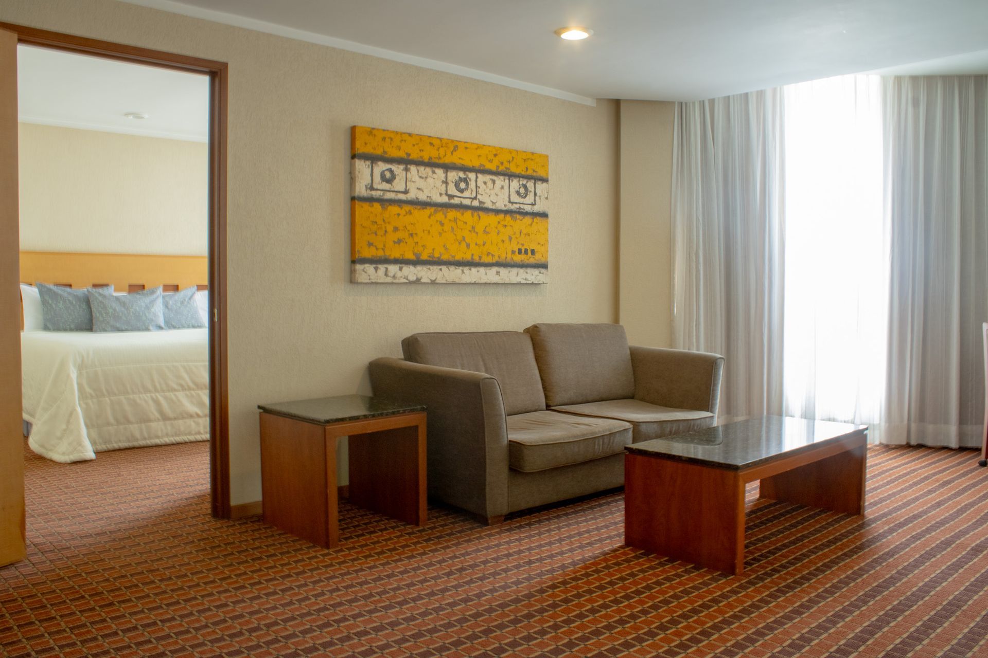 La suite del hotel cuenta con un sofá beige y una mesa de centro de madera