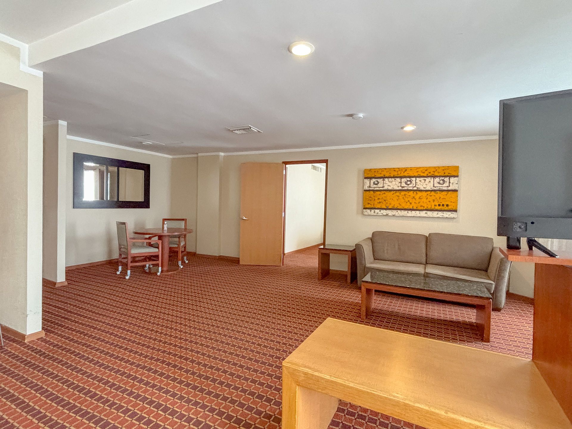 Una suite de hotel con un sofá color canela, una pequeña mesa de comedor con dos sillas