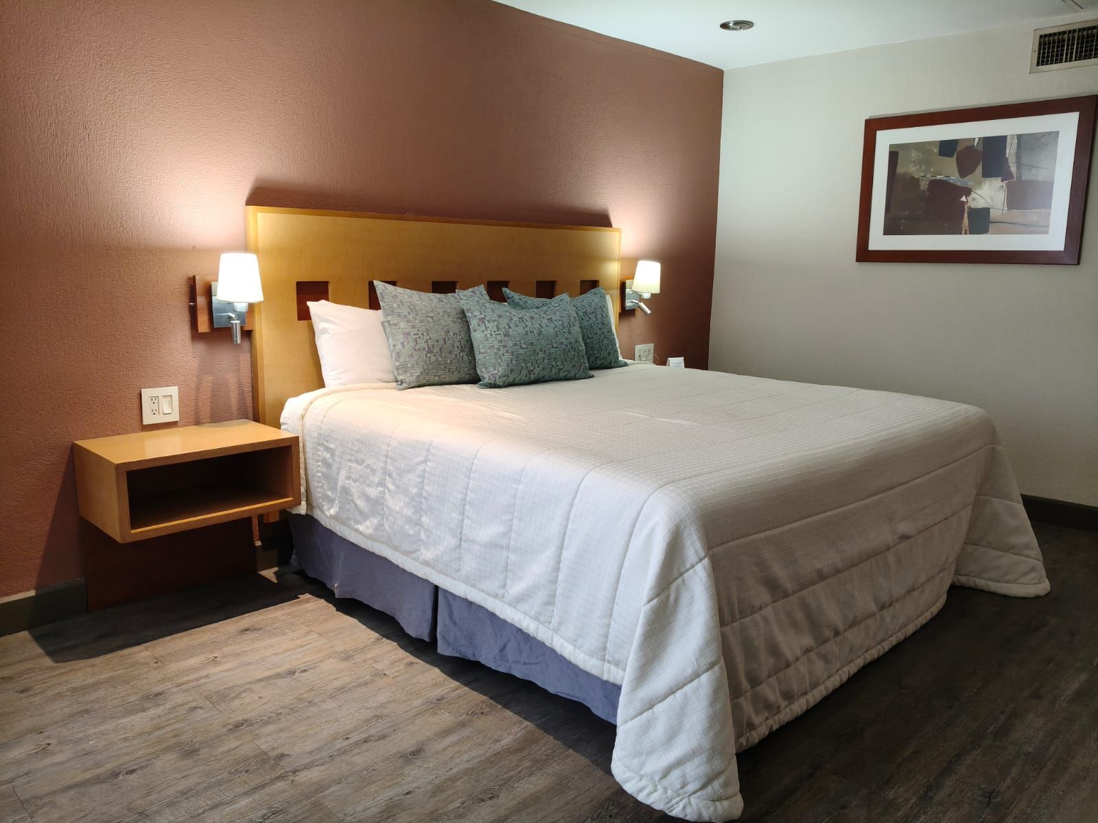 Una cama bien hecha con un edredón blanco y almohadas estampadas