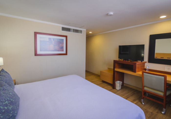 Una habitación de hotel con una cama con sábanas moradas, un escritorio y televisión