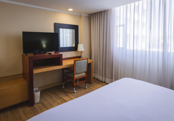 Una habitación de hotel con un televisor sobre un escritorio de madera