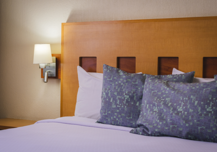 Una cama con sábanas moradas y almohadas estampadas de color azul 