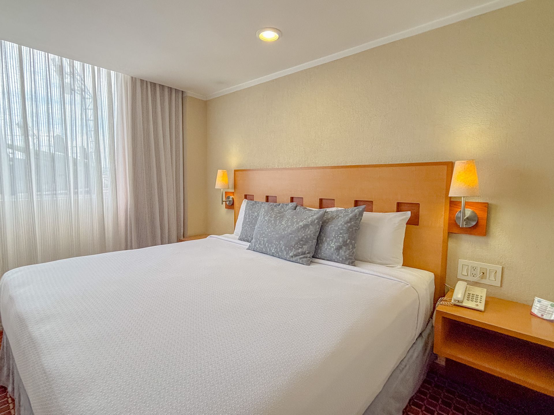 Una cama bien hecha con sábanas blancas y almohadas grises 