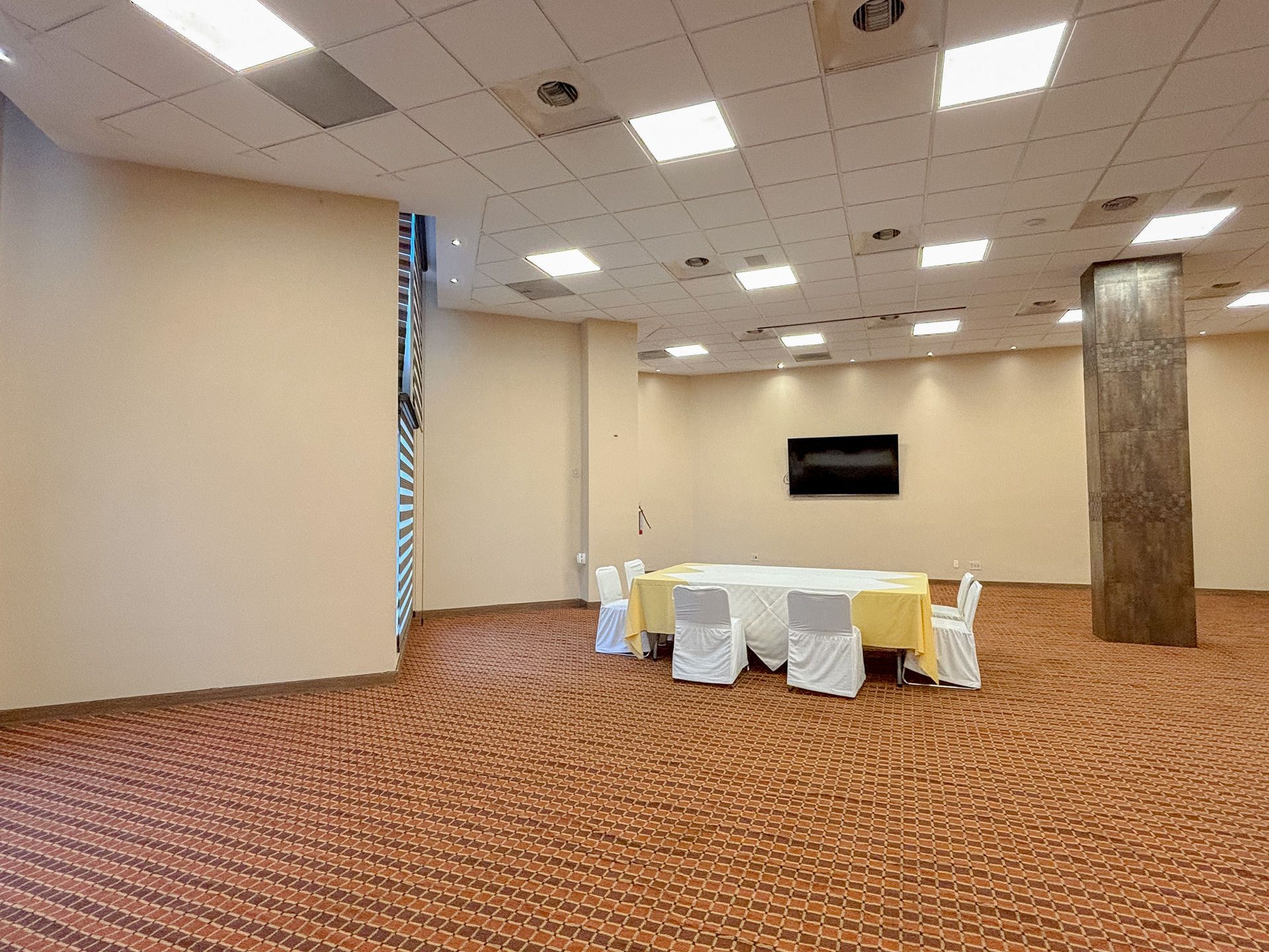 Una sala de conferencias amplia y vacía con una mesa color crema