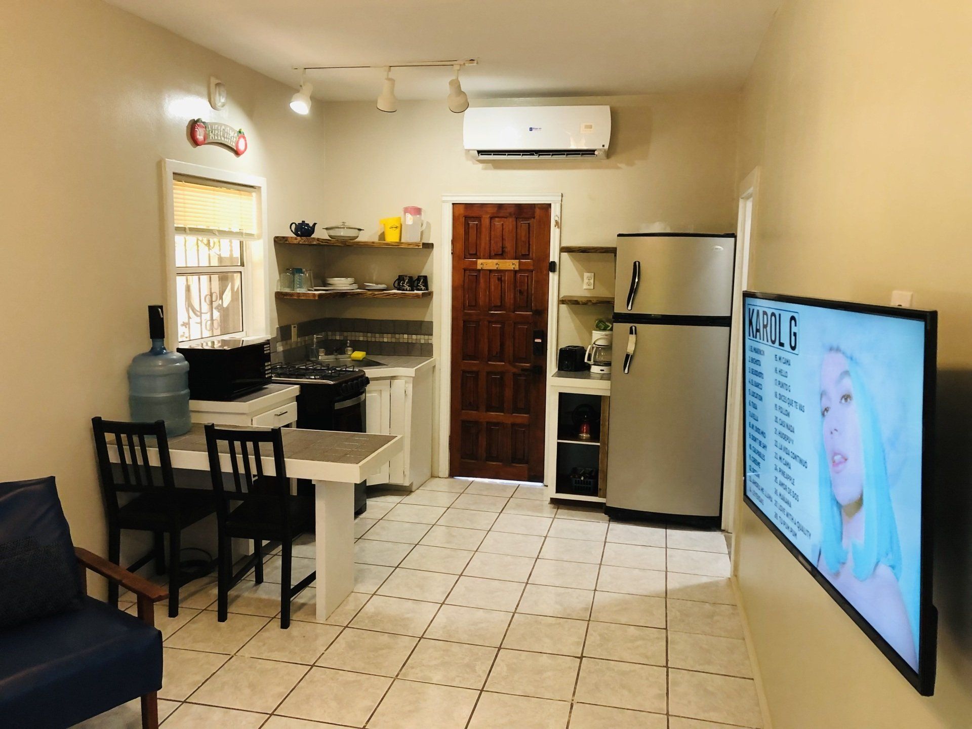 A small apartment with a kitchen, dining table, and TV.