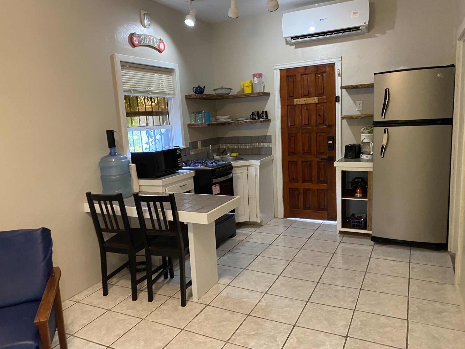 Small kitchen with white table, black chairs, stainless steel fridge, and a water dispenser.