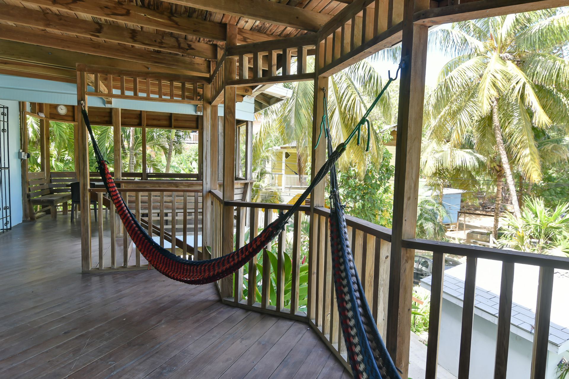 Wooden porch with two hammocks overlooking tropical trees.
