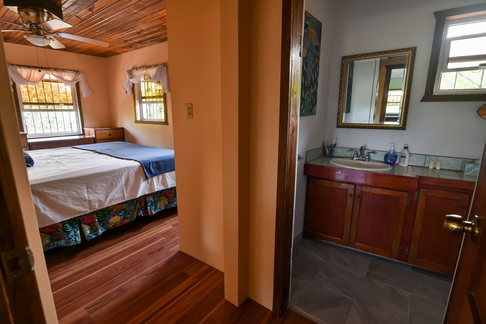 Bedroom and bathroom connected by a hallway. Bedroom has two beds, bathroom has vanity.
