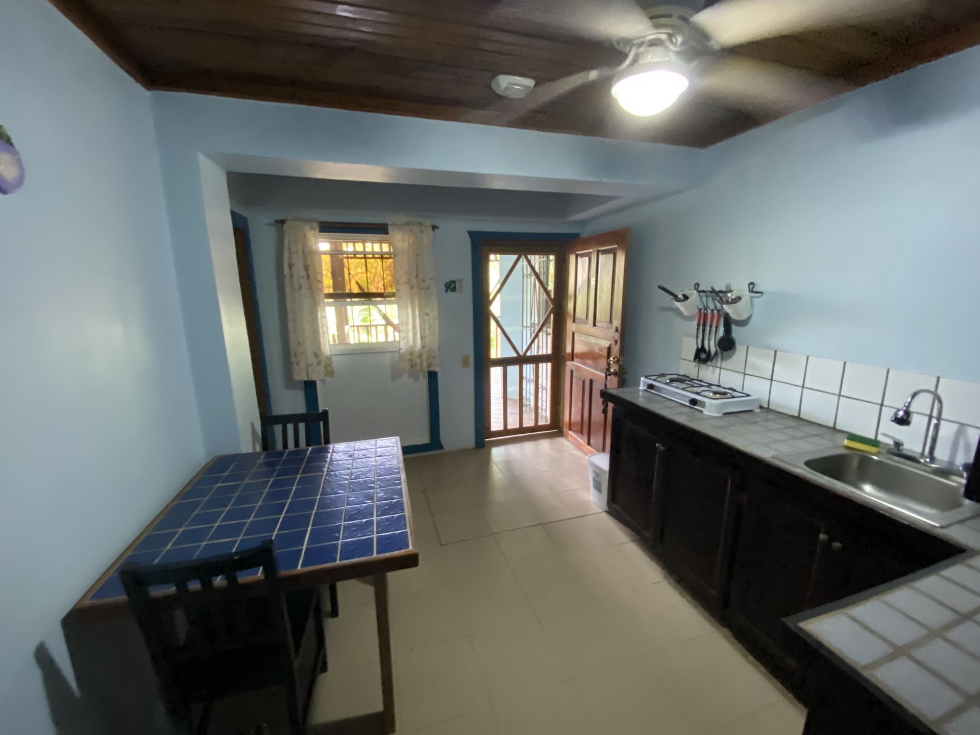 Small kitchen with blue walls, a dark wood ceiling, and a tiled table.