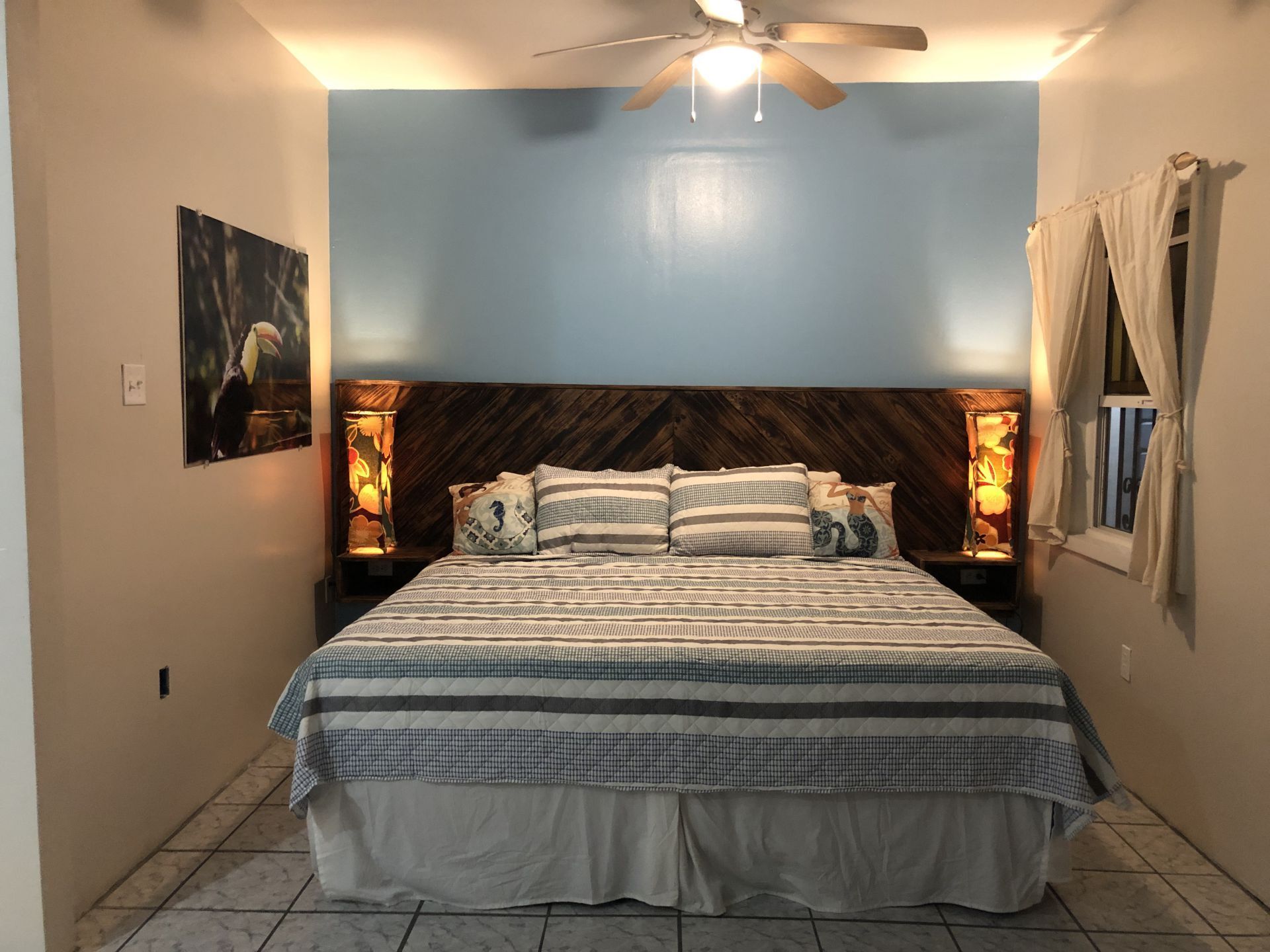 Bedroom with a large bed, blue accent wall, rustic headboard, and artwork.