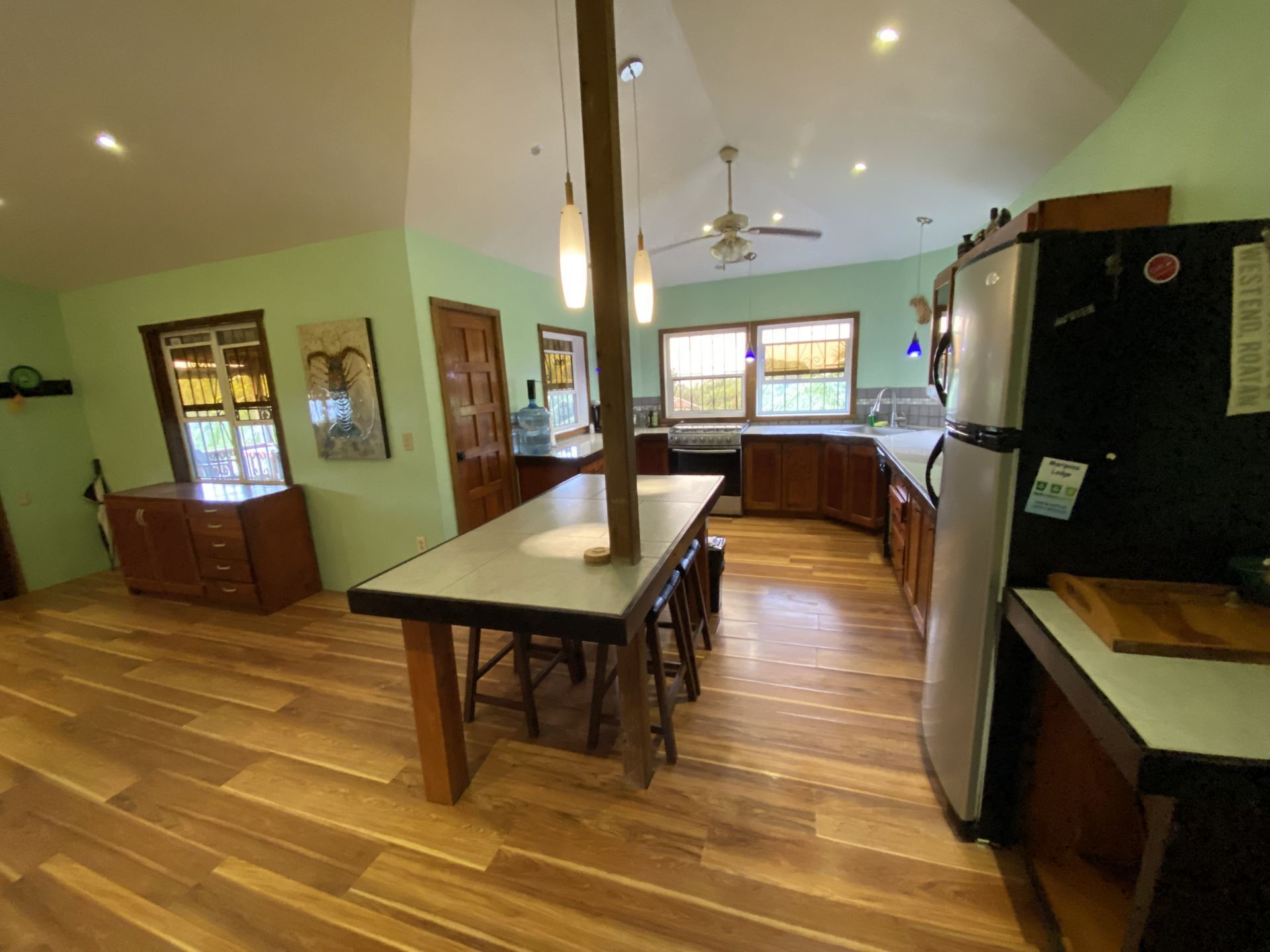 Kitchen with wood floors, green walls, and a long island with stools.