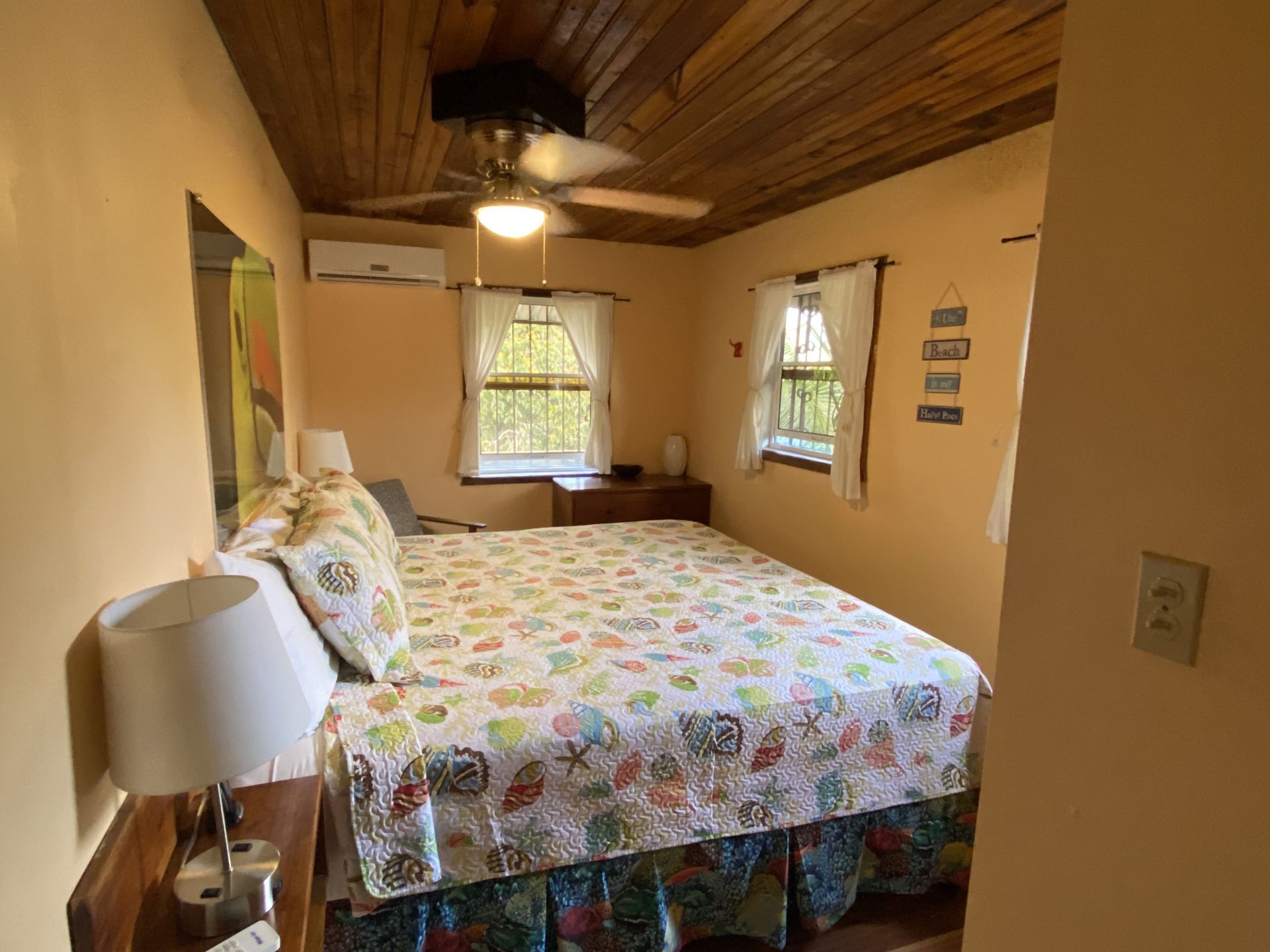 Bedroom with bed, nightstands, windows, and wooden ceiling.
