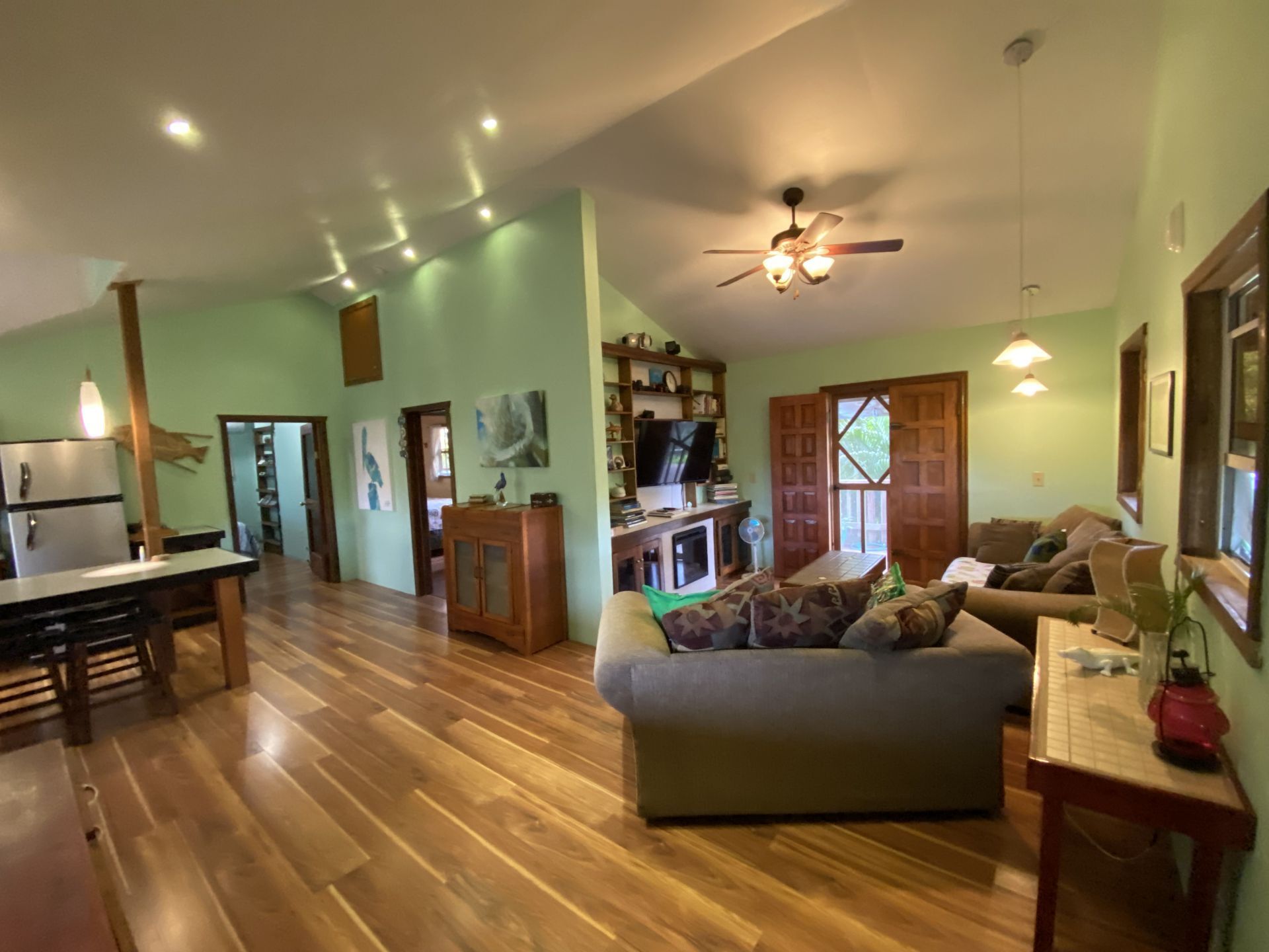 Open concept living area with hardwood floors, green walls, and brown furniture.
