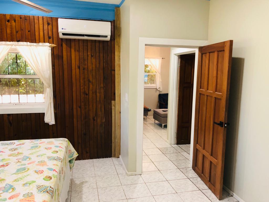Bedroom with wood paneling, bed, doorway to another room, and air conditioning unit.