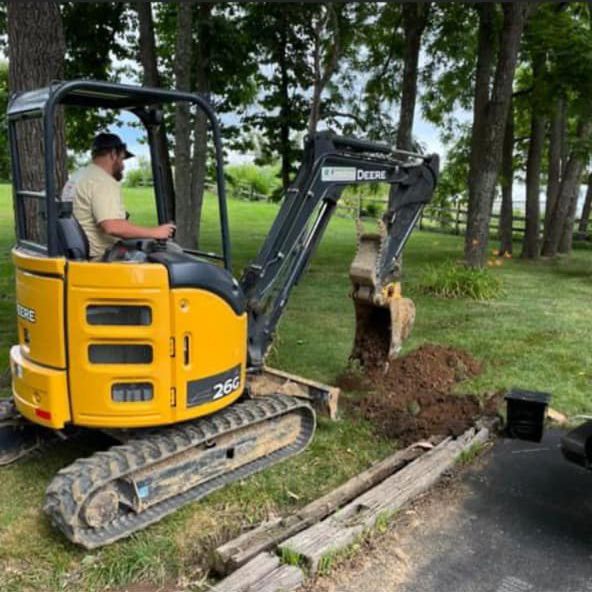 A Man Driving A Small Excavator In A Yard — Chesterton, IN — Claycor Construction