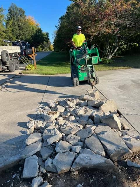 A Man Driving A Green Tractor Next To A Pile Of Rocks — Chesterton, IN — Claycor Construction