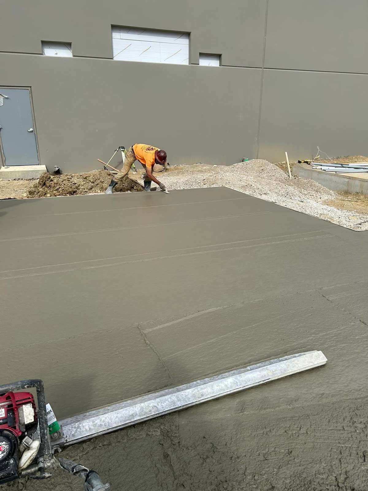 A Man Is Leveling A Concrete Surface In Front Of A Building — Chesterton, IN — Claycor Construction