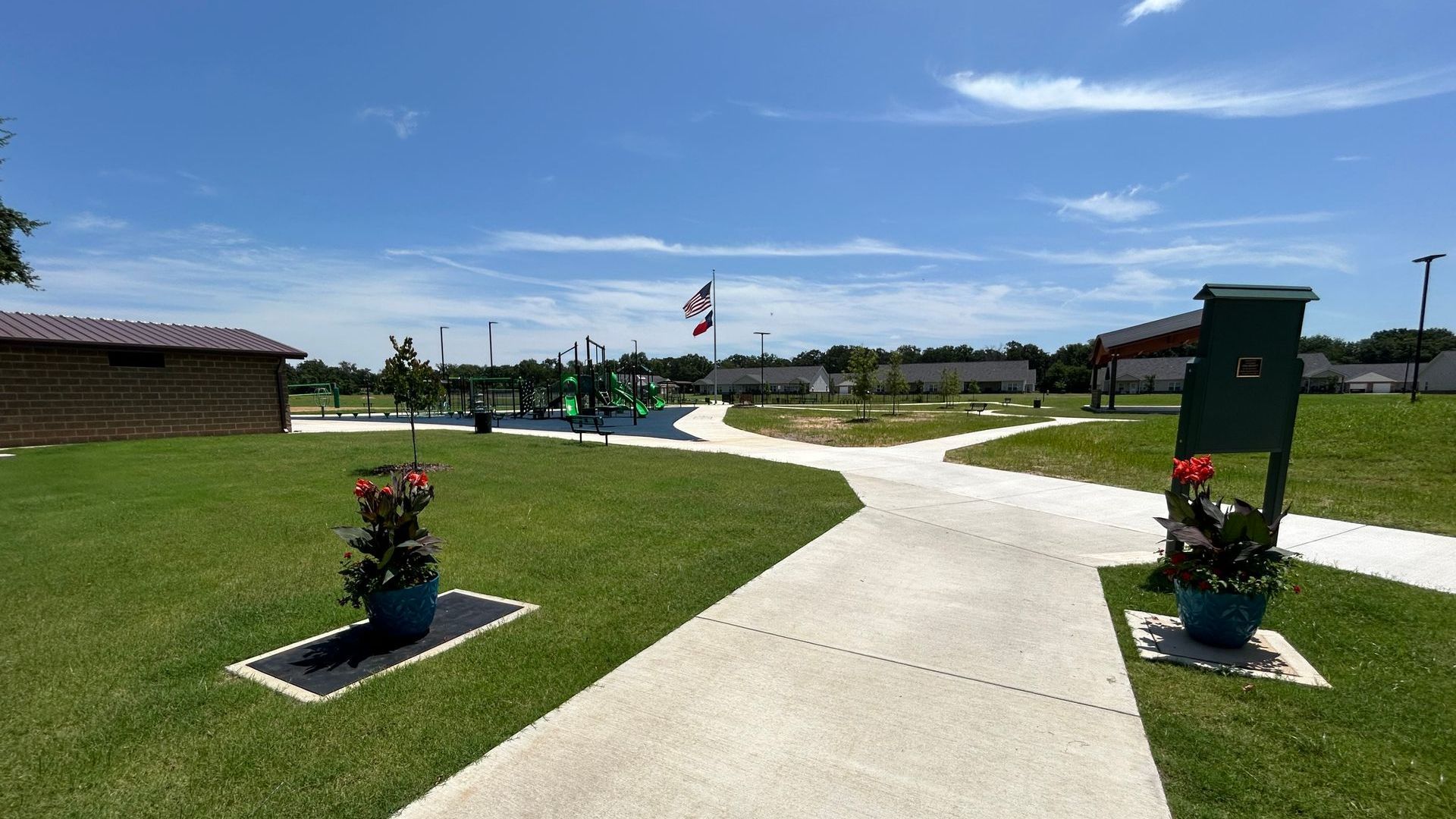 Two potted plants are on the sidewalk in a park