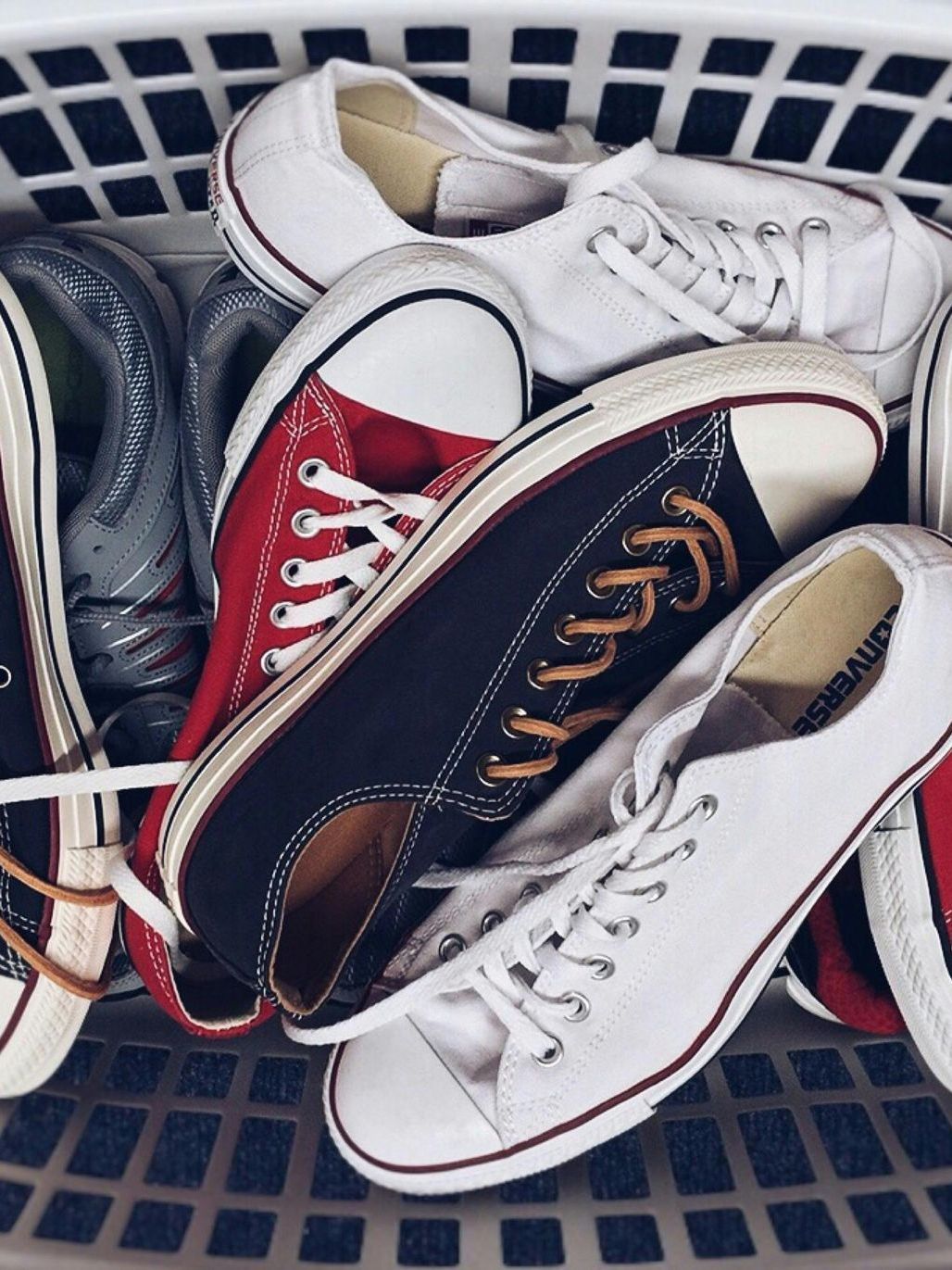 A basket filled with a variety of shoes including converse