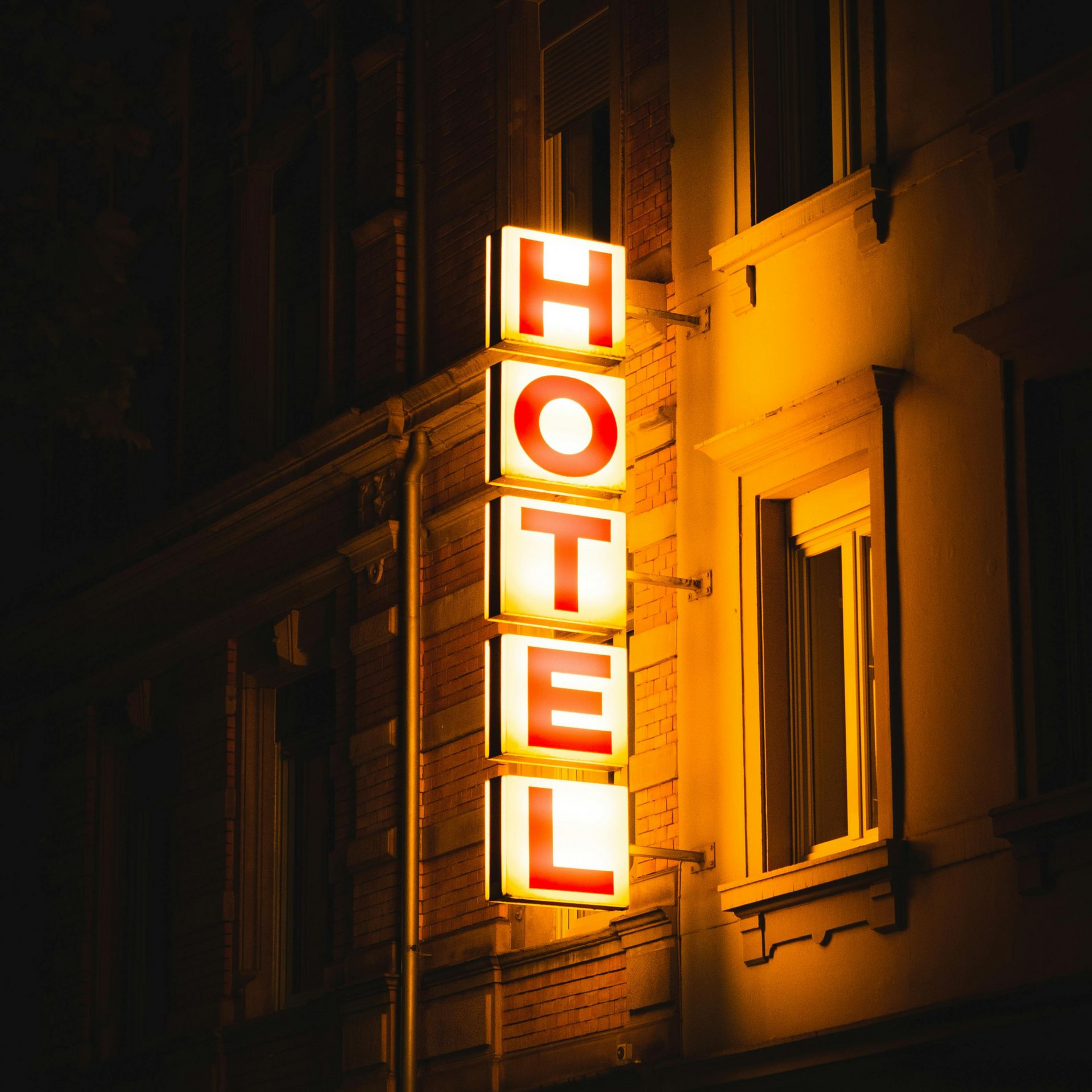Illuminated vertical HOTEL sign on a dark building at night