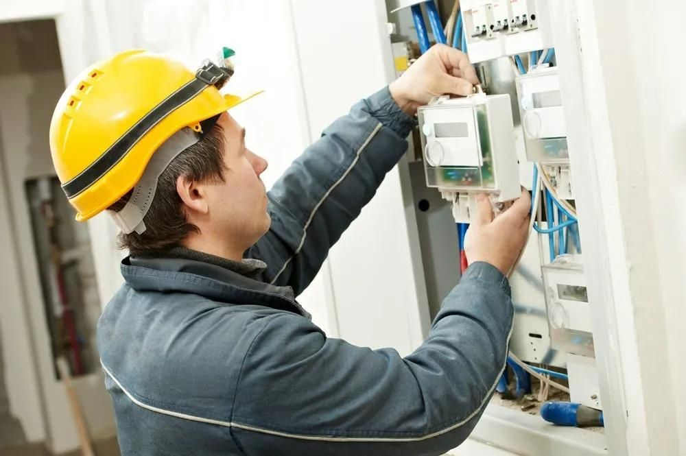 A Man Wearing a Hard Hat is Working on an Electrical Box — Clifford Electrical in Ballina, NSW