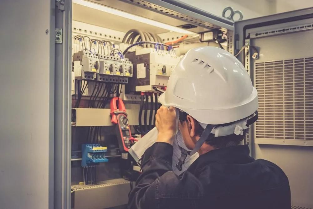 A Man Wearing a Hard Hat is Working on an Electrical Box — Clifford Electrical in Ballina, NSW