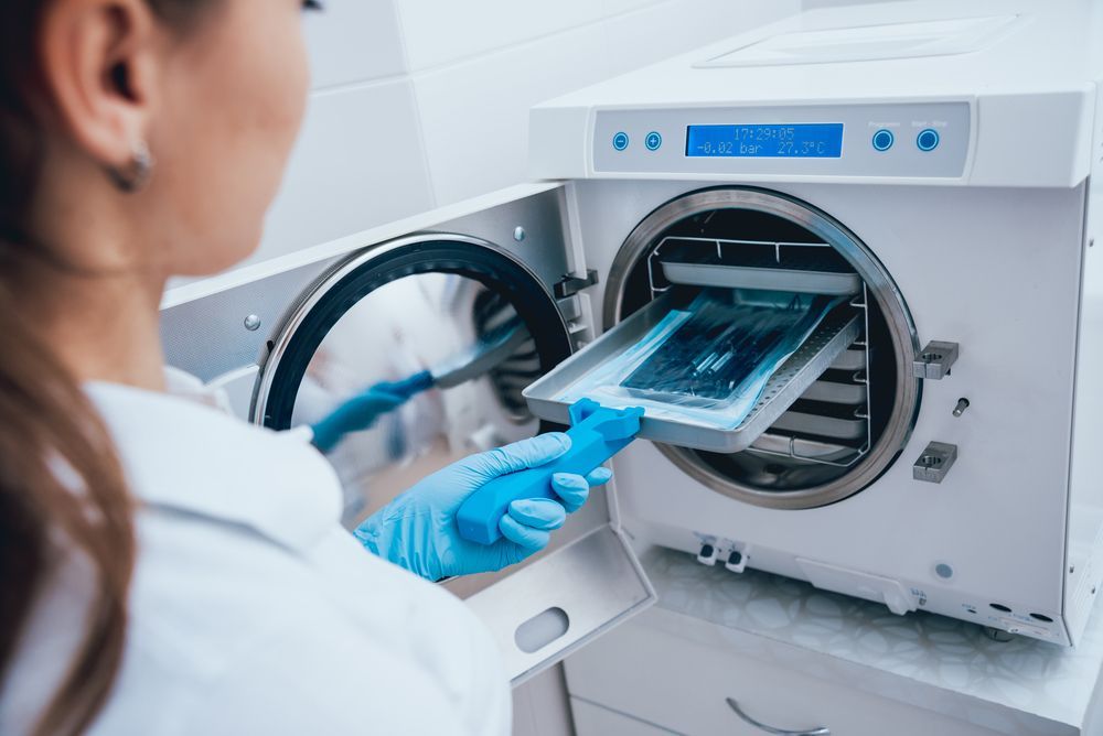 A Dentist is Using a Machine to Sterilize Dental Instruments — Clifford Electrical in Ballina, NSW