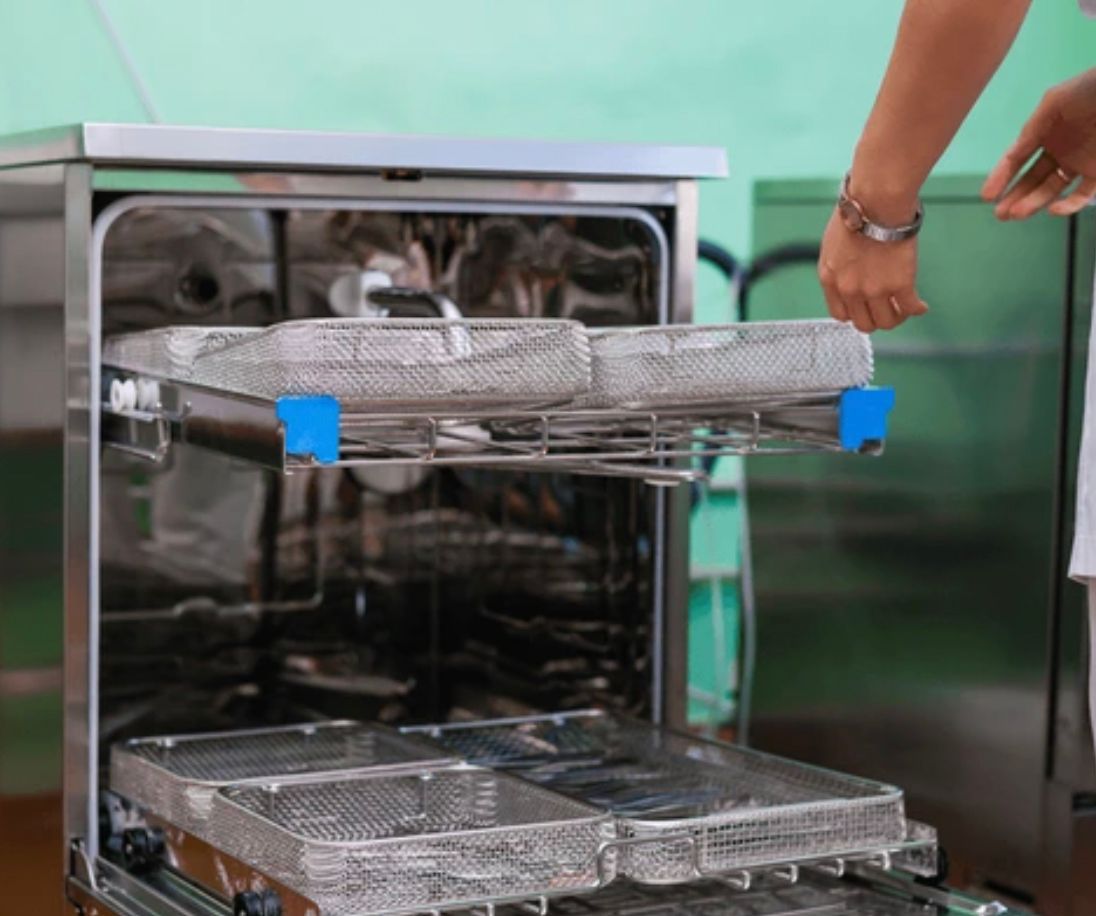 A Nurse is Loading Trays Into a Dishwasher — Clifford Electrical in Ballina, NSW