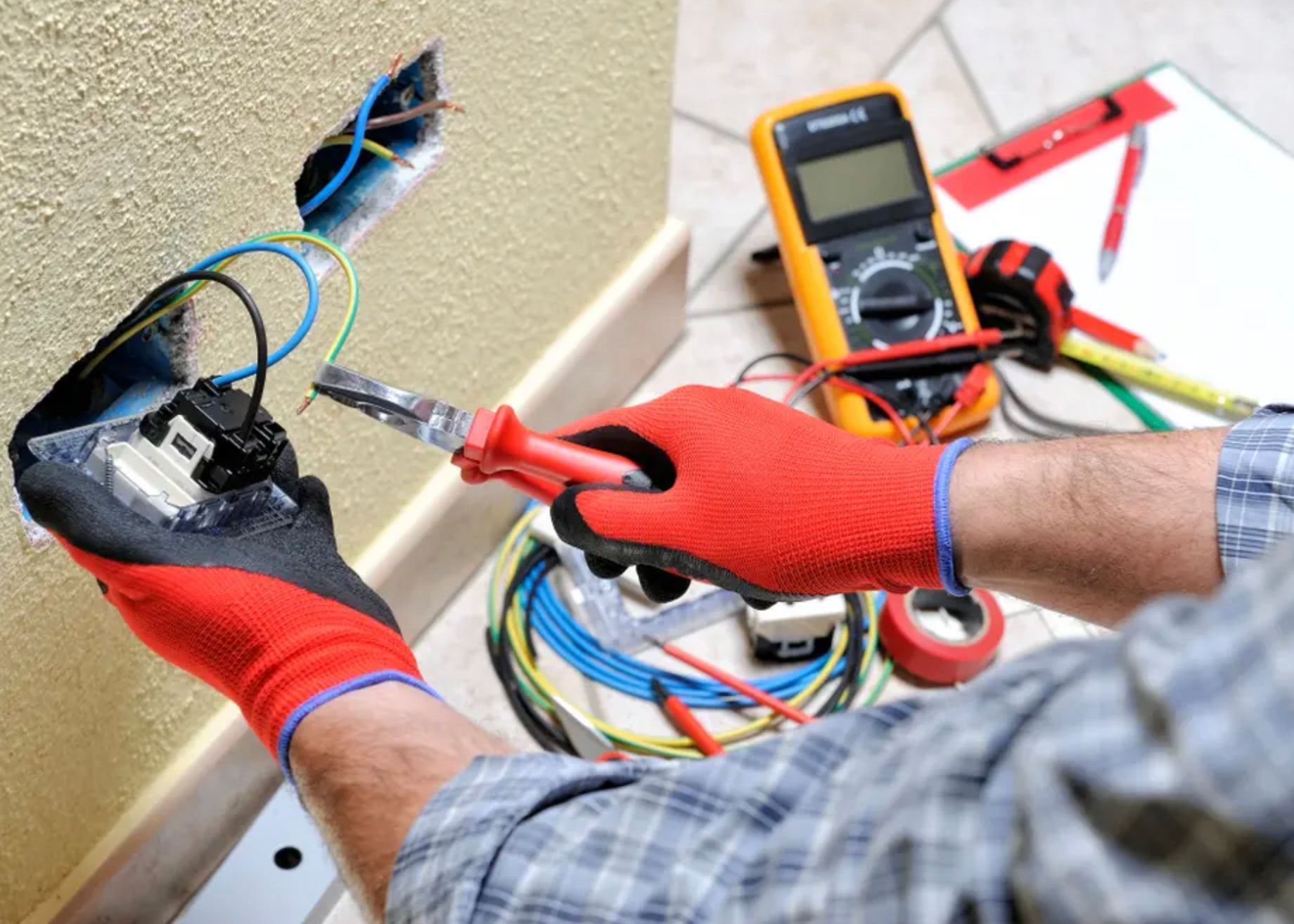 A Man Wearing Red Gloves is Working on an Electrical Outlet — Clifford Electrical in Byron Bay, NSW