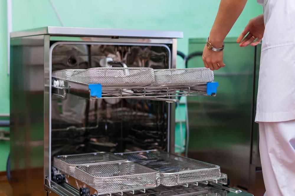 A Nurse is Loading Trays Into a Dishwasher — Clifford Electrical in Ballina, NSW