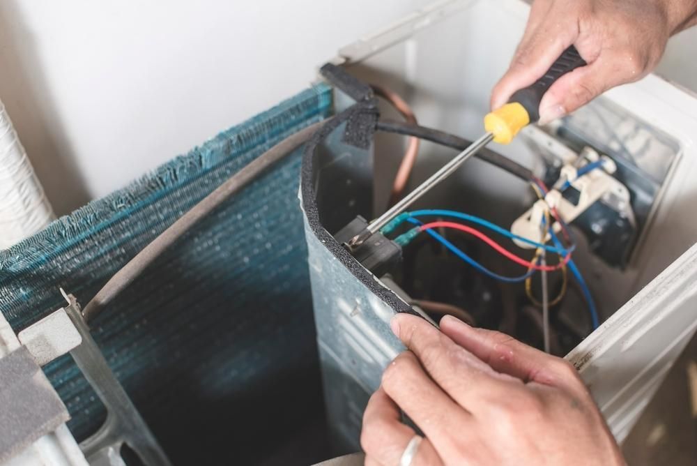 A Person is Fixing an Air Conditioner With a Screwdriver and Pliers — Clifford Electrical in Ballina, NSW