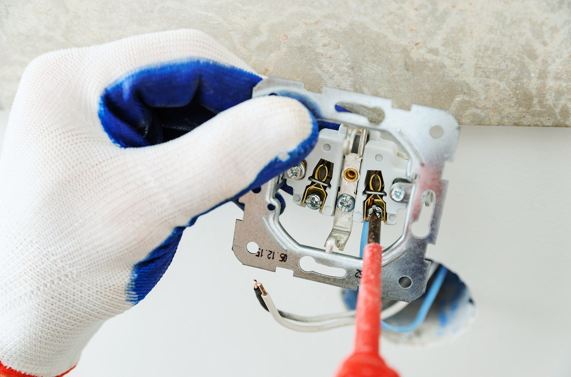 A Person is Fixing a Light Switch With a Screwdriver — Clifford Electrical in Ballina, NSW