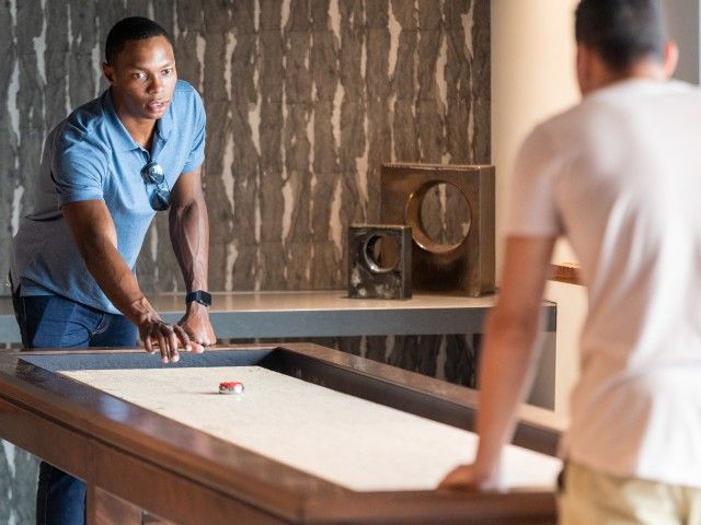 Friends playing shuffleboard at The Q.