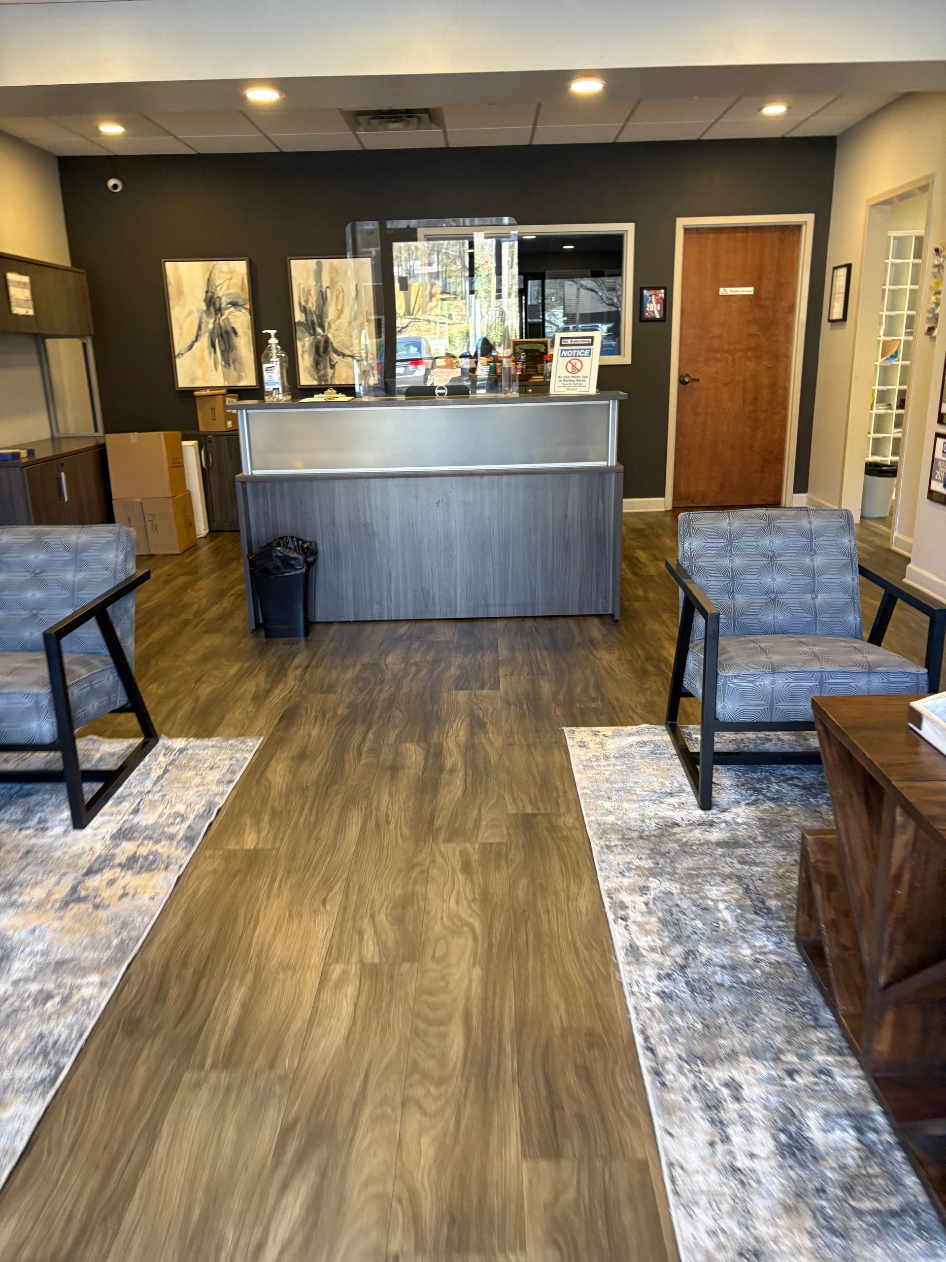 A waiting room with a desk , chairs , and a rug.