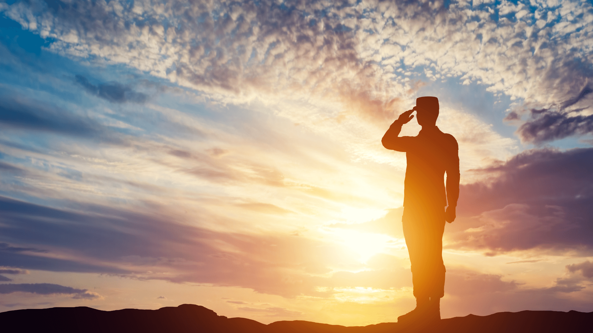 A silhouette of a soldier saluting at sunset.
