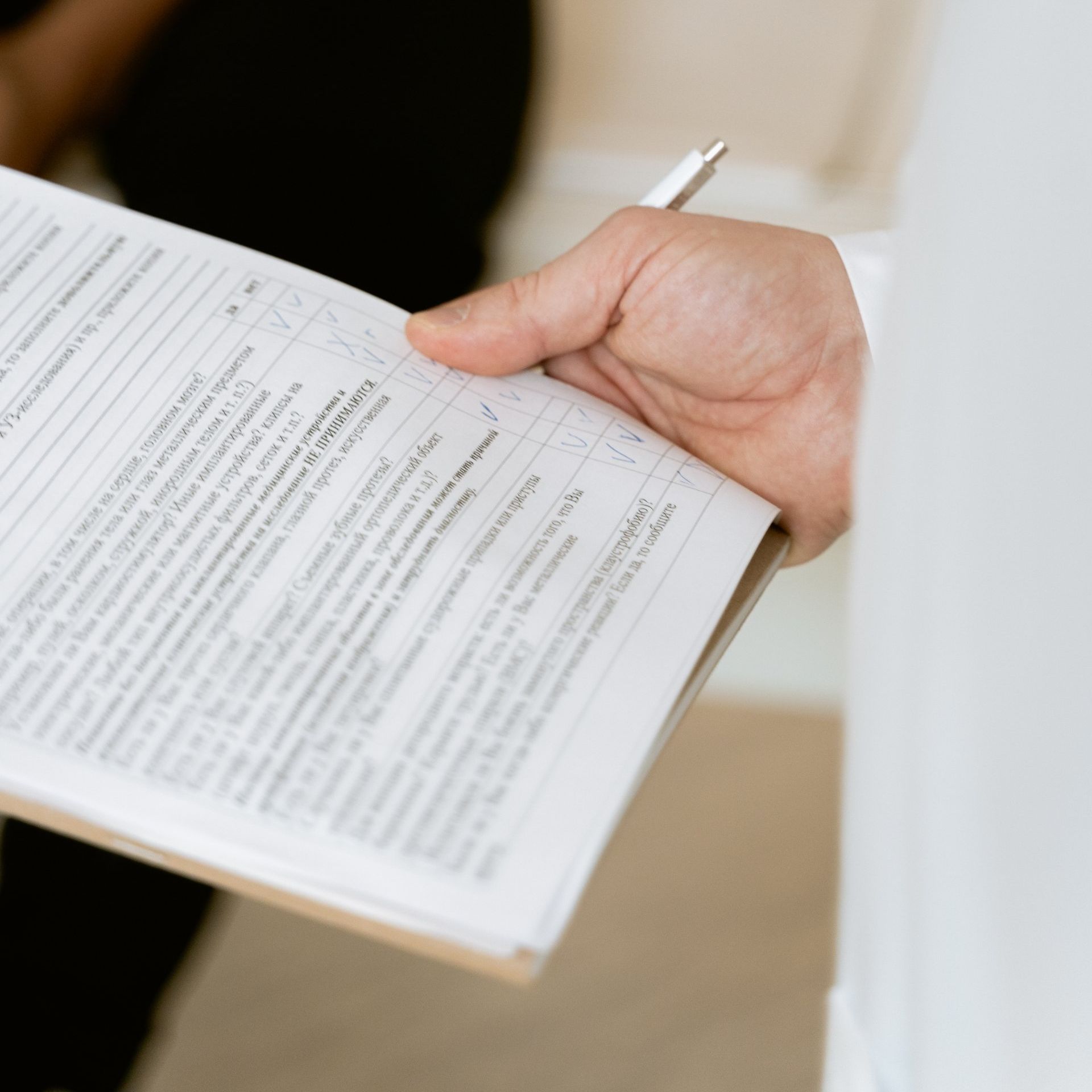 A person is holding a piece of paper with a pen in their hand