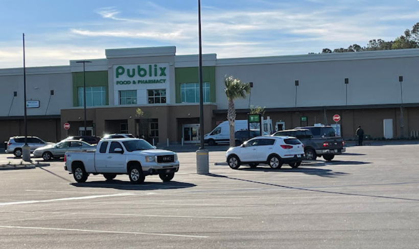 A row of cars are parked in front of a publix store.