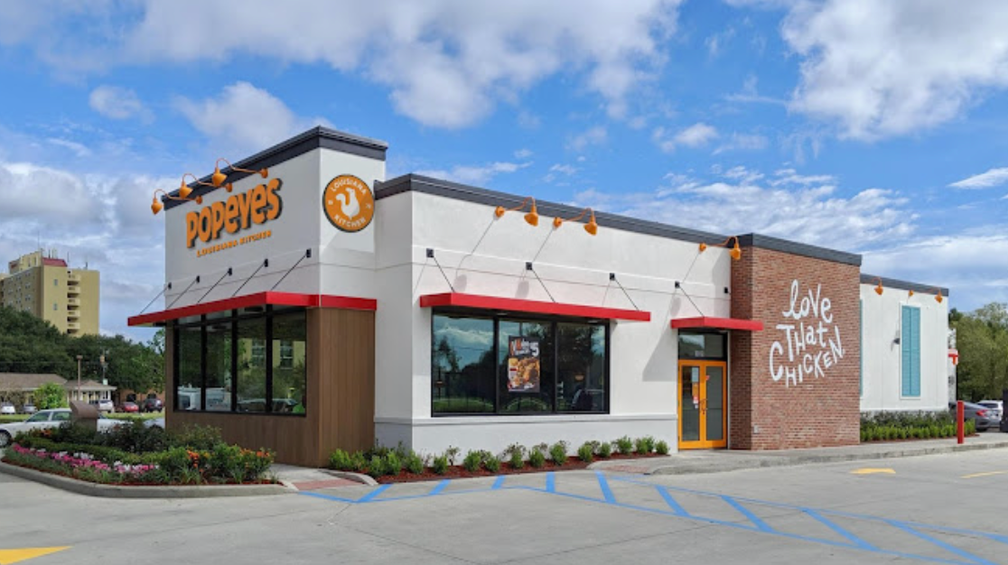 A fast food restaurant with a parking lot in front of it.