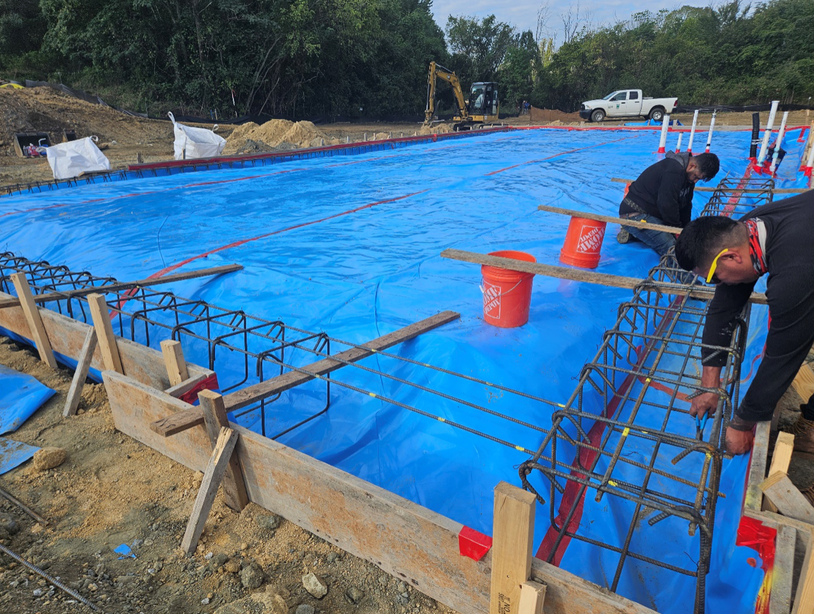 A group of construction workers are working on a blue tarp.