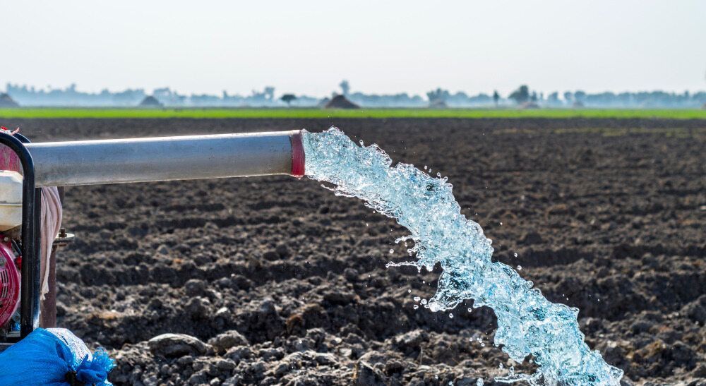 Water Gushes From a Metal Pipe Onto Dark, Tilled Soil in a Field — Humpty Doo Hardware in Humpty Doo, NT