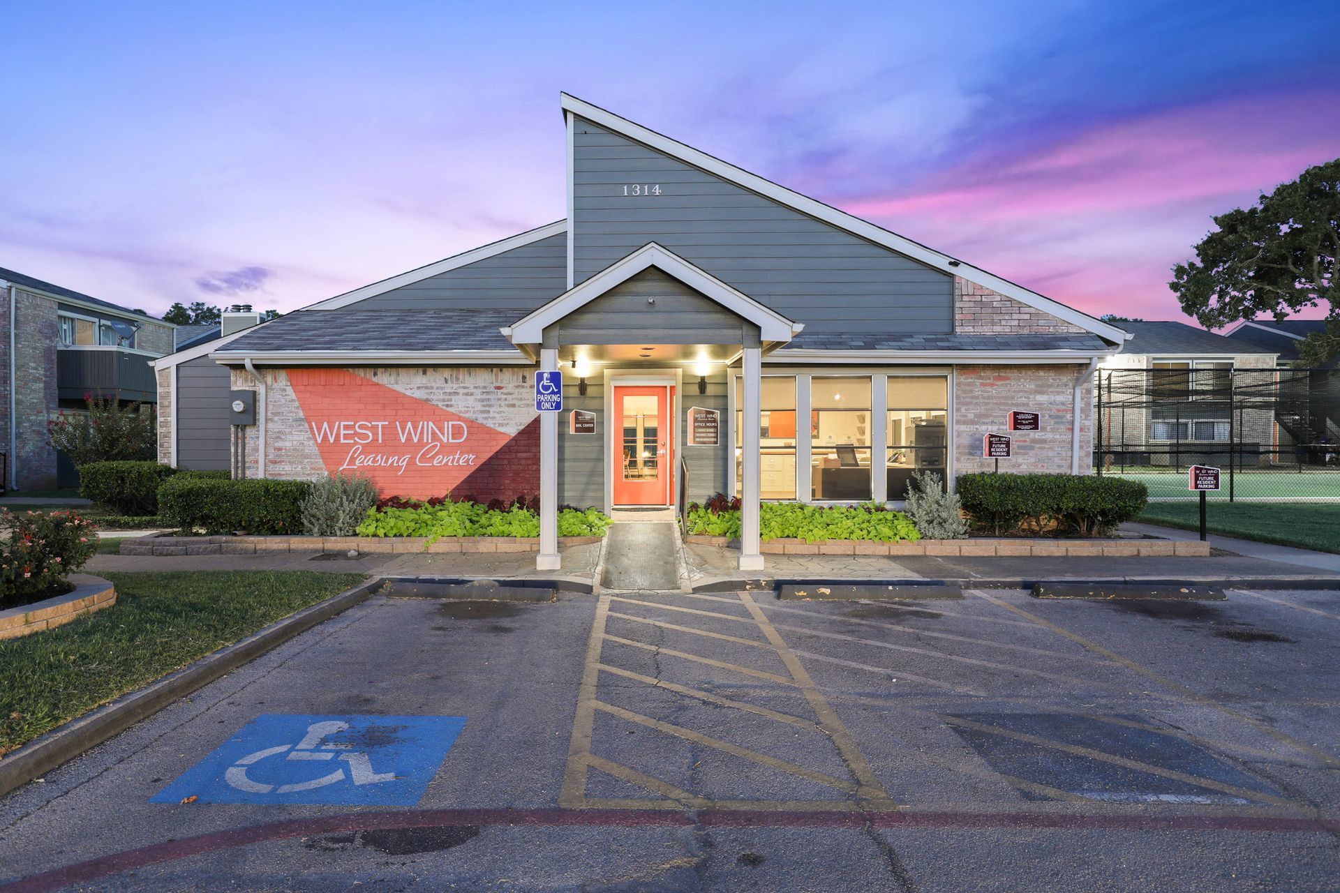 Apartment leasing office with red door, accessible parking, and sign 