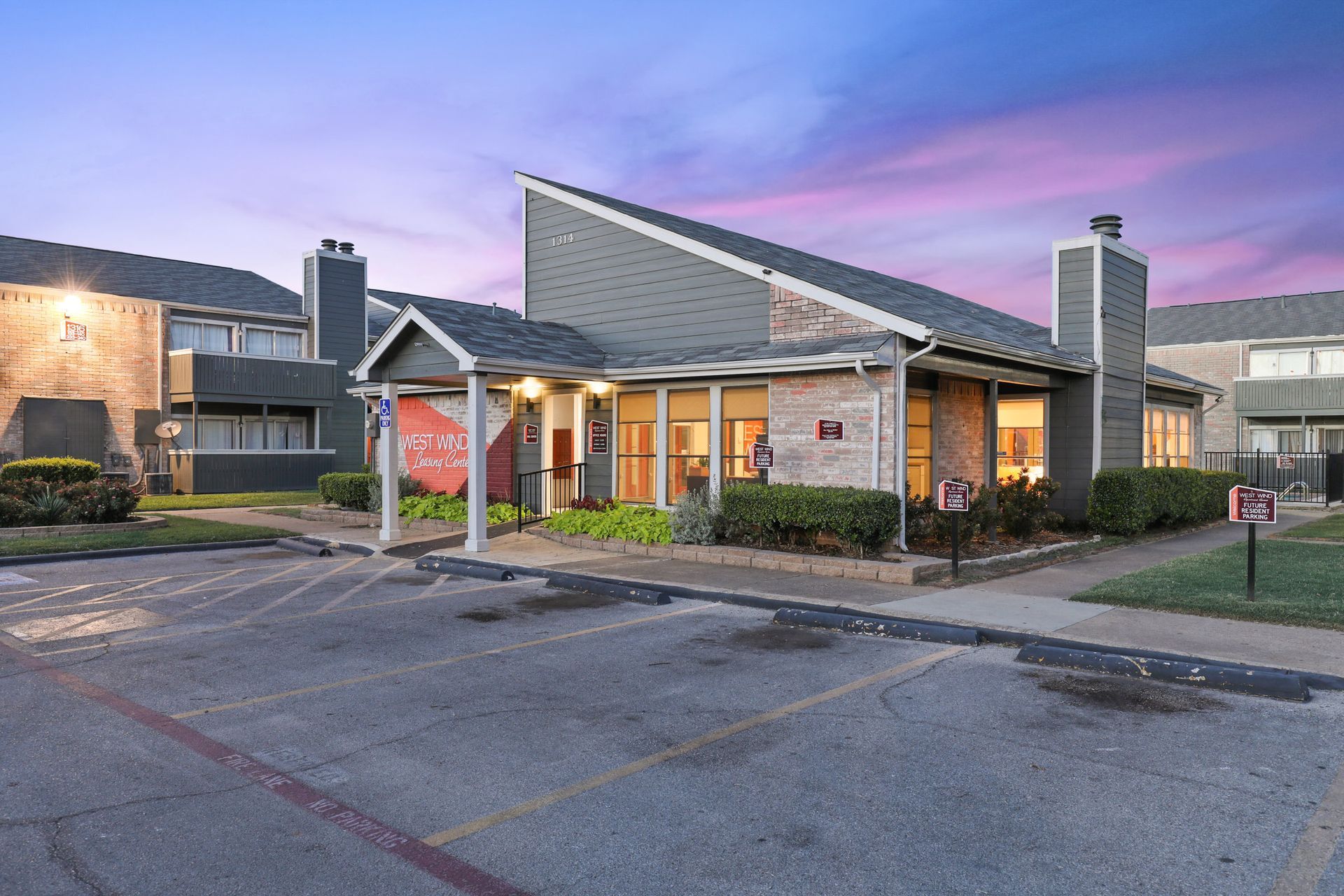 Apartment building with office, parking, and a colorful sunset sky.