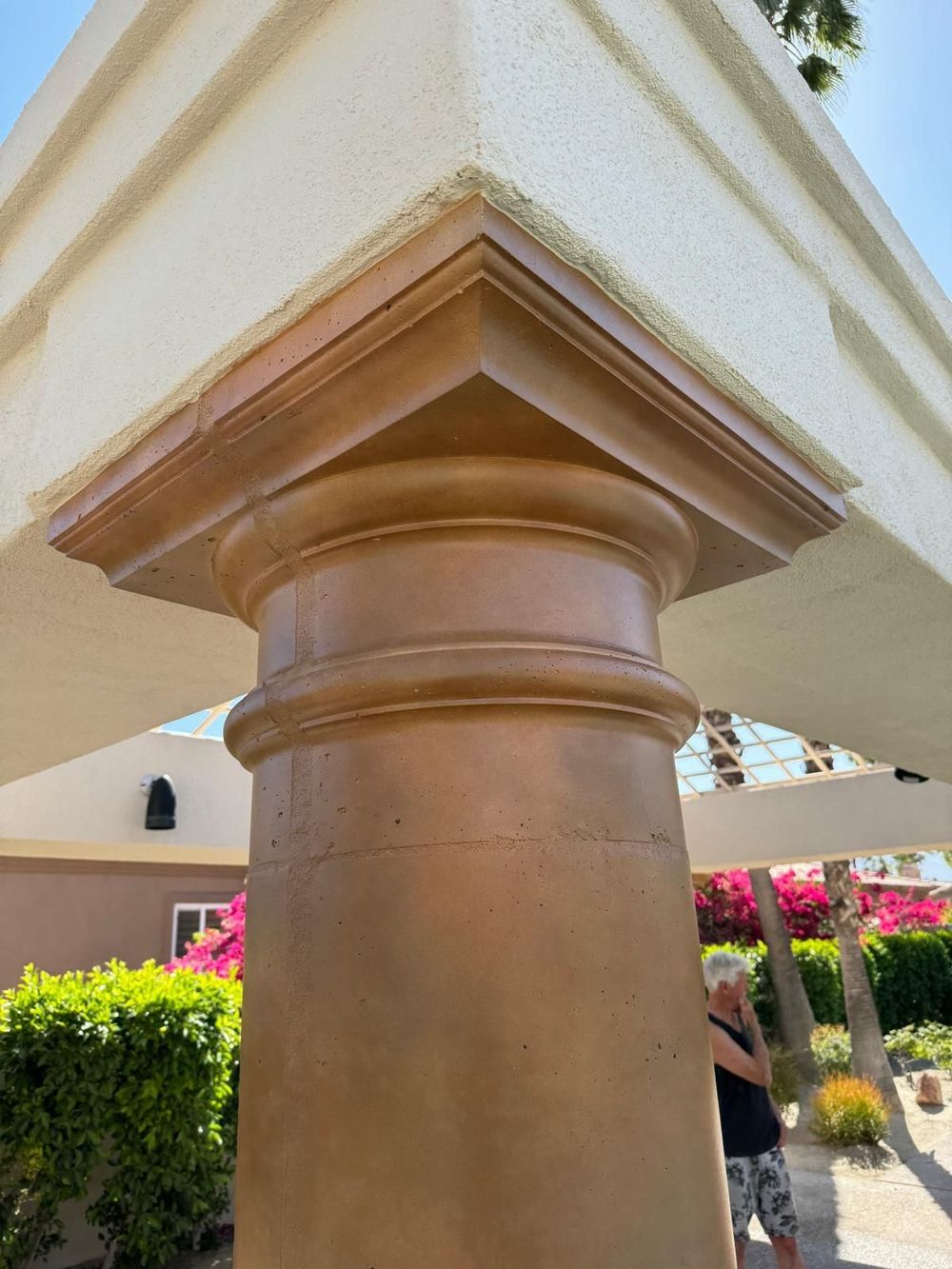 A woman is standing next to a pillar in front of a building.