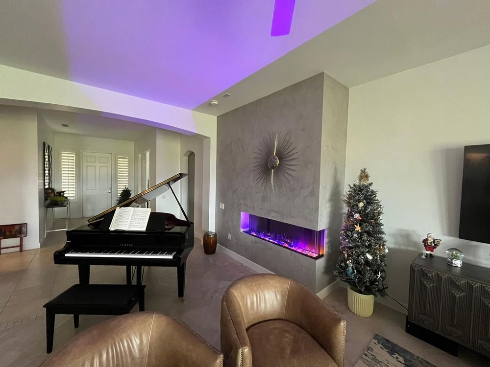 A living room with a piano , chairs , a fireplace and a christmas tree.