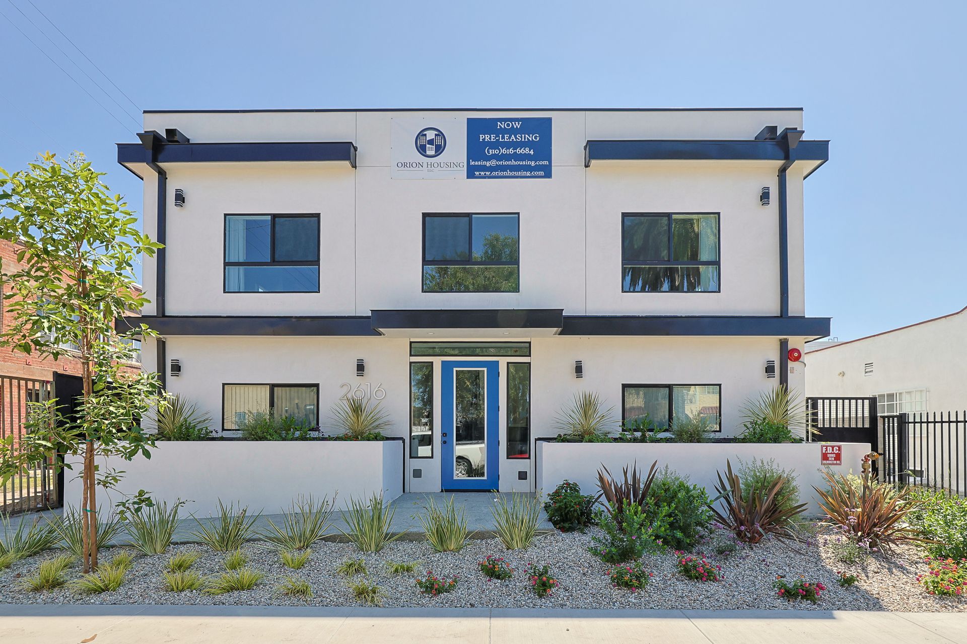 This image showing a beautiful double story house in a blue and offwhite color with a small garden in front of him.